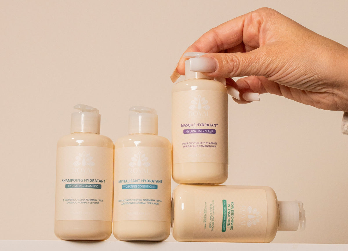 ROYAL Hydrating Shampoo, Hydrating Conditioner, Hydrating Mask and 10 in 1 Leave-In Conditioner arranged on a soft beige background, with a hand holding the mask.