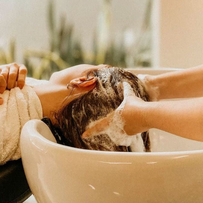 Hair being shampooed at a salon wash basin during a professional hair care service.